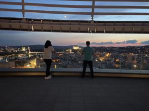 two people standing on top of a building looking at the city at SAG Sky Park Residence Free parking and Wi-Fi in Bratislava