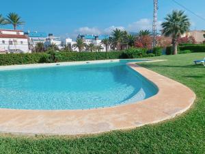 een zwembad in een tuin met gras en palmbomen bij Apartamento exclusivo en la playa in Denia