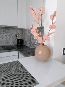 um vaso com flores cor-de-rosa num balcão na cozinha em Apartman Enio em Vukovar