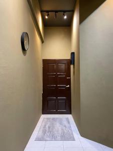 a hallway with a wooden door with a rug on the floor at The Concrete Cave - Plaza Temerloh in Temerloh