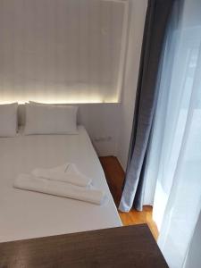 a white bed with a towel on it next to a window at Petmeza Top Aigio City F in Aigio
