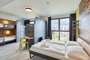 a bedroom with a bed and a desk and a window at MEININGER Hotel Köln West in Cologne