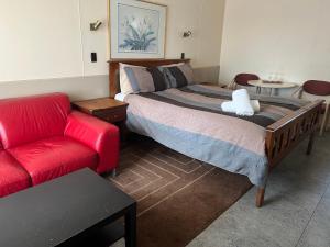 a bedroom with a bed and a red couch at Woodmans Hill Motel in Ballarat