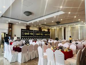un salón de banquetes con sillas y mesas blancas y gente en Quê Tôi 2 Hotel, en Soc Trang