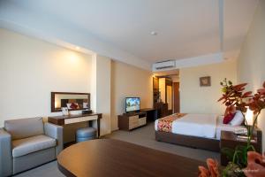 a hotel room with a bed and a chair and a table at Wiltop by BENCOOLEN in Jambi