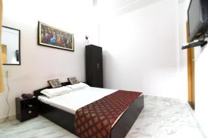 DS Residency Varanasi في فاراناسي: غرفة نوم بسرير مع صورتين على الحائط