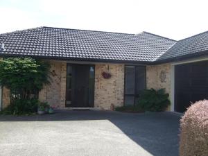 a brick house with a black door and a driveway at Jade Bed & Breakfast in Blenheim