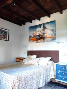 a bedroom with a bed with four paintings on the wall at Casita Roja sin cocina in Cercedilla