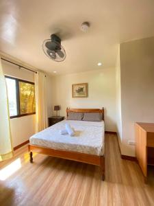 1 dormitorio con 1 cama y ventilador de techo en Tessie's Home Stay Bed & Breakfast en Puerto Princesa