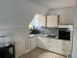 a kitchen with white cabinets and a sink at Ferienwohnung De ole School mit eigener Sauna! in Fehmarn