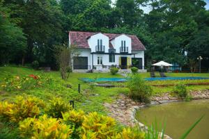 a white house with a red roof next to a pond at Interconnection Ba Vì Venuestay in Hanoi