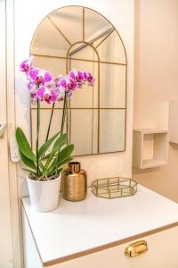 - un comptoir de salle de bains avec un vase orné de fleurs violettes dans l'établissement 50m Gem - 400m Gare: garage privé, terrasse, wifi, à Grenoble