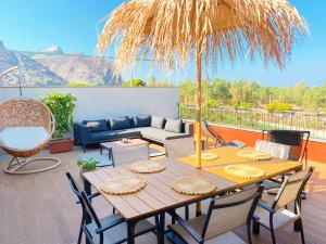 eine Terrasse mit einem Tisch und einem Strohschirm in der Unterkunft La Casa Di Rosa in Oliveri