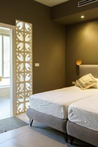 1 dormitorio con 2 camas y una pared con ventana en סיני 48 מלון דירות בוטיק en Vered Yeriho