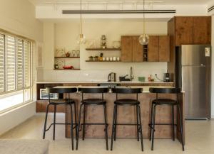 a kitchen with bar stools and a refrigerator at סיני 48 מלון דירות בוטיק in Vered Yeriho