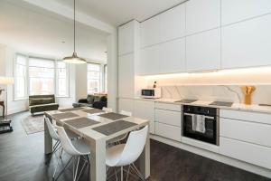 a kitchen with white cabinets and a table and chairs at Stylish 2 bedroom at Hammersmith in London
