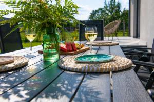 Wingris - dom wczasowy nad Jeziorem Wigry في Bryzgiel: طاولة خشبية عليها أكواب من النبيذ الأبيض