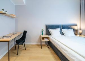 um quarto com uma cama, uma secretária e uma cadeira em City Break Plac Wolności 6 Aparthotel em Poznań