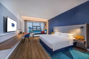 a bedroom with a large white bed and a blue wall at Holiday Inn Express Xiamen Airport Zone, an IHG Hotel in Xiamen