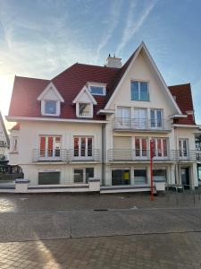 a large white building with a red roof at De Haan in De Haan