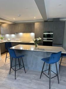 a kitchen with a table and two blue chairs at Cameron Coach House Modern Property in Murrayfield Edinburgh in Edinburgh