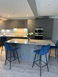 kuchnia ze stołem i 2 niebieskimi krzesłami w obiekcie Cameron Coach House Modern Property in Murrayfield Edinburgh w Edynburgu