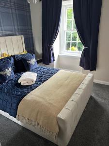 a bedroom with a bed with blue sheets and a window at Cameron Coach House Modern Property in Murrayfield Edinburgh in Edinburgh
