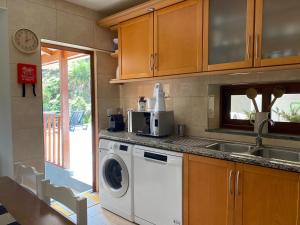 een keuken met een wasmachine en een wastafel bij Penha D'Águia Villa by LovelyStay in Porto da Cruz