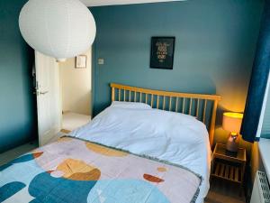 1 dormitorio con 1 cama con pared azul en Whitstable contemporary cosy home with parking, en Kent