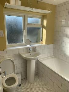 a bathroom with a toilet and a sink and a tub at Whitstable contemporary cosy home with parking in Kent