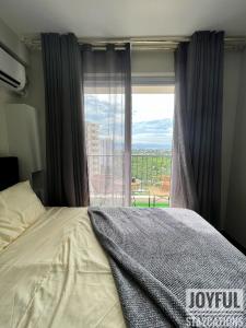 ein Schlafzimmer mit einem Bett und einem großen Fenster in der Unterkunft Condo with resort-like living, everyday in Lapu Lapu City