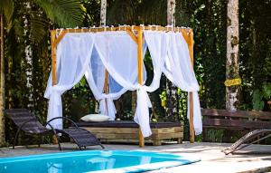 a canopy over a bed next to a pool at Sitio do Sol suíte romântica in Guabiruba