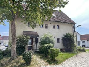 Una casa blanca con un árbol delante. en Gemütliche Apartments mit Balkon, en Niederstotzingen