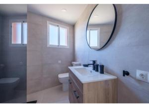 uma casa de banho com um lavatório, um espelho e um WC. em costa sur em Vinarós