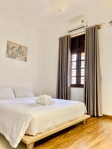 een slaapkamer met een bed met witte lakens en een raam bij The Hideaway Alley Bui Vien in Ho Chi Minh-stad