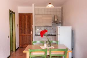 a kitchen with a table with a vase of red flowers at Glorious Residence Le Pavoncelle one Bedroom sleeps four child num1450 in Santa Teresa Gallura