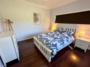 een slaapkamer met een bed met een blauw en wit dekbed bij Jacaranda Cottage in Broadwater