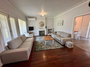 Sala de estar con 2 sofás y mesa de centro en Jacaranda Cottage, en Broadwater