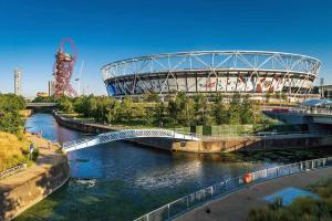 un puente sobre un río con un estadio de fondo en New Bubble Apartments, en Londres