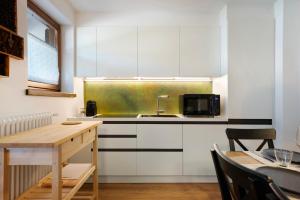 une cuisine avec des placards blancs et une table en bois dans l'établissement La casa di Marco, à Cavalese