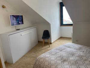 1 dormitorio con 1 cama y TV en la pared en Brisas del mar en Isla de Arosa
