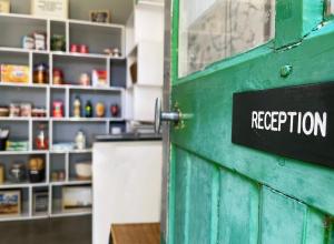 eine grüne Tür mit einem Schild, das den Empfang liest in der Unterkunft Camping Canal de Berry in Saint-Amand-Montrond