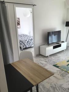 uma sala de estar com uma mesa e uma televisão e uma cama em Vue mer, 2 pièces lumineux em Nice
