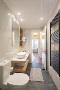 a white bathroom with a toilet and a sink at Liston Bliss Suite in Corfu Town