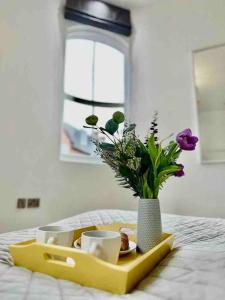 uma bandeja com copos e um vaso com flores numa cama em Chic Living At The Chancery em Leicester