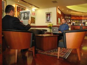 dos hombres sentados en un bar con sus portátiles en Hotel Due Leoni, en Sacile