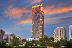 a tall building with lights on it in a city at Haikou Mingguang Shengyi Hotel (Previous Mingguang International Hotel) in Haikou