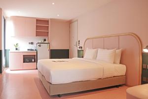 1 dormitorio con cama blanca y cocina pequeña en The Quarter Ratchathewi by UHG, en Pom Prap