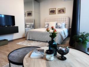 Azur Alegria Studio - free parking & pool في ساينت قسطنطين وهيلينا: غرفة معيشة مع سرير وطاولة مع مزهرية مع الزهور