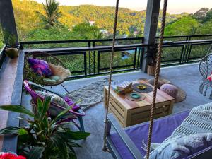 eine Veranda mit einer Schaukel und einem Tisch auf dem Balkon in der Unterkunft Wonderland Jungle Hostel in Ko Tao